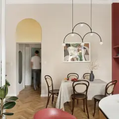 Złoty łuk nad drzwiami to stylowy sposób, by czym wykończyć łuk w salonie. Wnętrze z jadalnią i nowoczesnym oświetleniem.