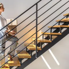 Kobieta z pudełkami wspina się po nowoczesnych schodach wachlarzowych.