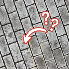 Szare kostki brukowe, na których widać ślady ługowania. Strzałka i znaki zapytania sugerują, że coś się tu wydarzyło.