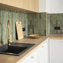 Naturalny, drewniany kolor blatu kuchennego pięknie komponuje się z zieloną, pionową mozaiką.
