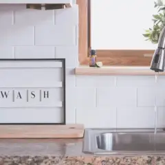 Napis "WASH" na tablicy między szafkami w kuchni, obok dozownika mydła i zlewu. Idealna inspiracja, co na ścianę w kuchni między szafkami.
