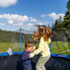 Dzieci skaczą na trampolinie w ziemi. Dowiedz się, jak zrobić taką trampolinę, by zapewnić im mnóstwo radości!