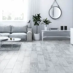 Jasny salon z szarą kanapą, białymi stolikami i podłogą imitującą drewno hikora.