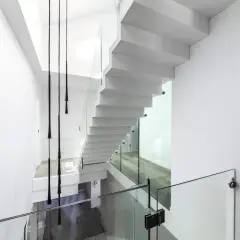 Nowoczesne białe schody z przeszklonymi balustradami. Zastanawiasz się nad schody cena za stopień?