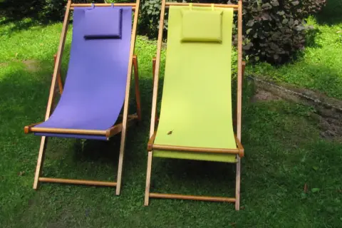 Dwa leżaki ogrodowe, jeden fioletowy, drugi zielony, czekają na wymianę materiału.