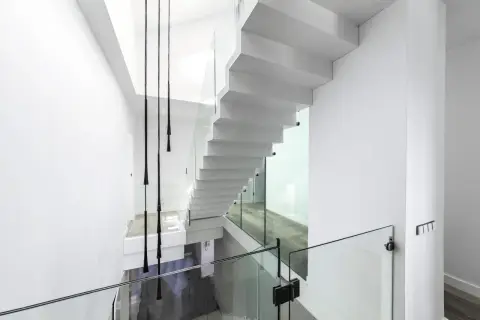 Nowoczesne białe schody z przeszklonymi balustradami. Zastanawiasz się nad schody cena za stopień?