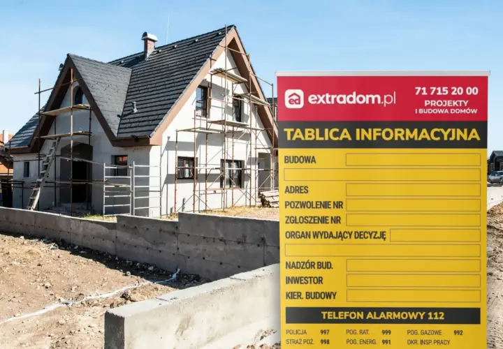 Tablica informacyjna budowy domu w trakcie prac, z widocznym rusztowaniem i fundamentami.