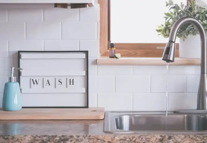 Napis "WASH" na tablicy między szafkami w kuchni, obok dozownika mydła i zlewu. Idealna inspiracja, co na ścianę w kuchni między szafkami.