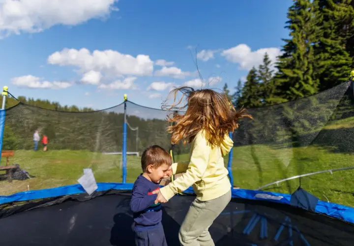 Dzieci skaczą na trampolinie w ziemi. Dowiedz się, jak zrobić taką trampolinę, by zapewnić im mnóstwo radości!