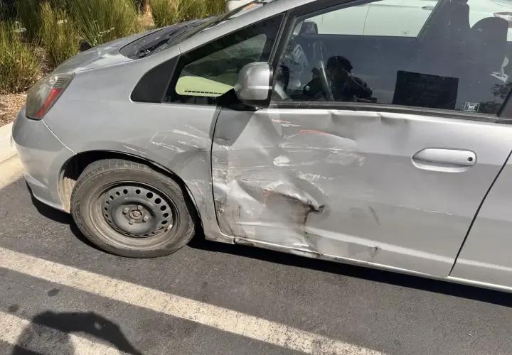Srebrne drzwi samochodu mocno wgniecione i porysowane. Zastanawiasz się, jak naprawić podrapane drzwi?