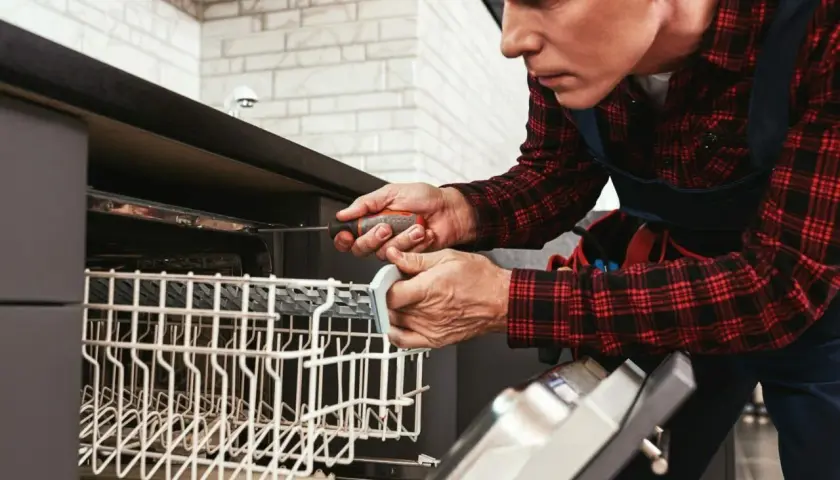 Fachowiec dokonuje zabezpieczenie blatu nad zmywarką, używając śrubokręta.