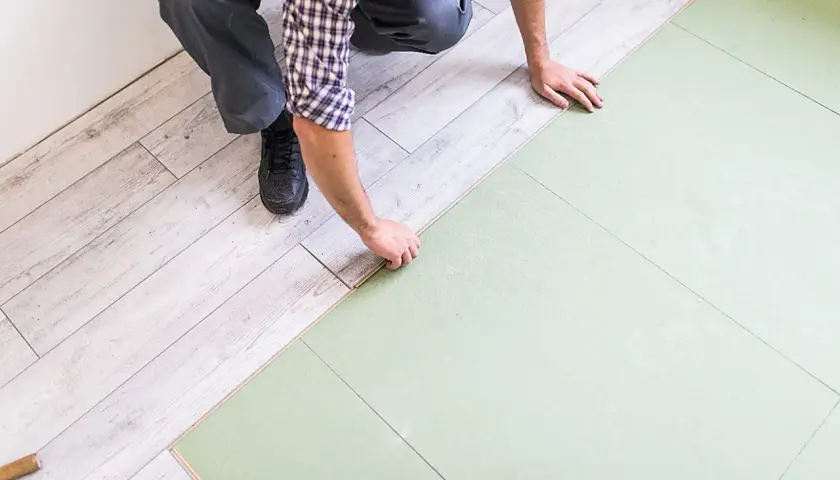 Układanie podłogi pływającej, co to jest? Montaż paneli laminowanych na zielonym podkładzie.