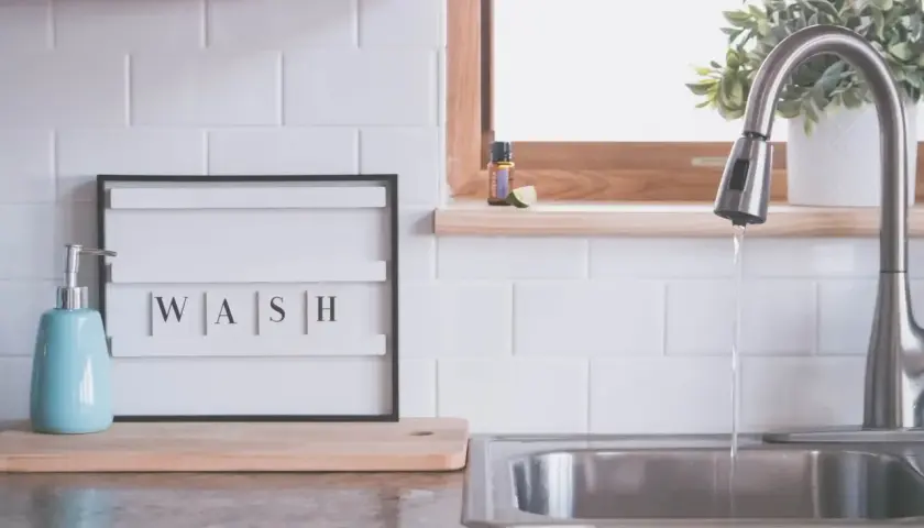 Napis "WASH" na tablicy między szafkami w kuchni, obok dozownika mydła i zlewu. Idealna inspiracja, co na ścianę w kuchni między szafkami.