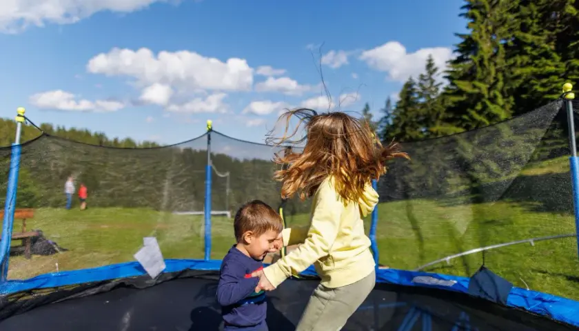 Dzieci skaczą na trampolinie w ziemi. Dowiedz się, jak zrobić taką trampolinę, by zapewnić im mnóstwo radości!