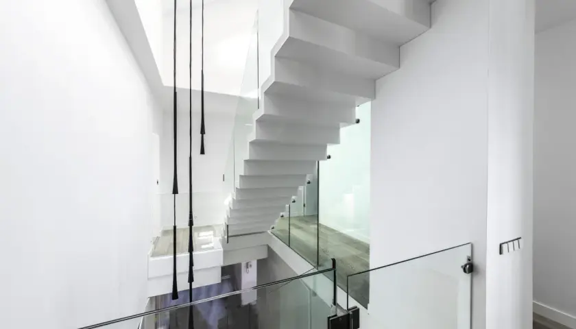 Nowoczesne białe schody z przeszklonymi balustradami. Zastanawiasz się nad schody cena za stopień?