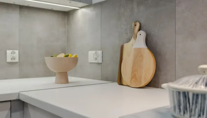Nowoczesna kuchnia z białym blatem, misą z cytrynami i drewnianymi deskami. Zastanawiasz się, ile kosztuje metr blatu kuchennego?