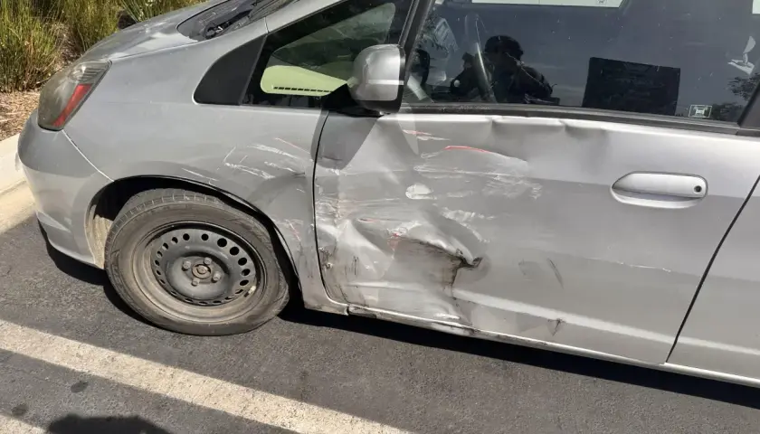 Srebrne drzwi samochodu mocno wgniecione i porysowane. Zastanawiasz się, jak naprawić podrapane drzwi?