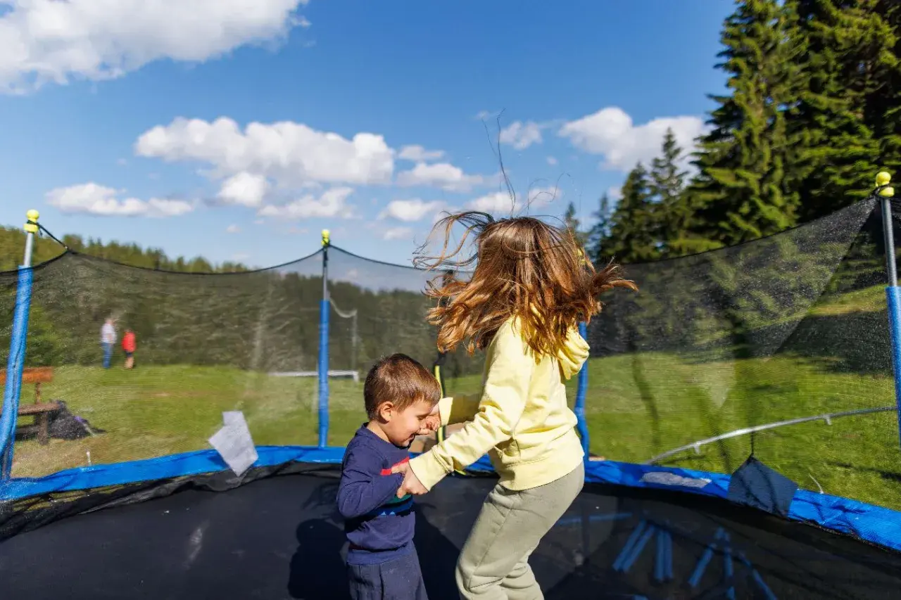 Dzieci skaczą na trampolinie w ziemi. Dowiedz się, jak zrobić taką trampolinę, by zapewnić im mnóstwo radości!