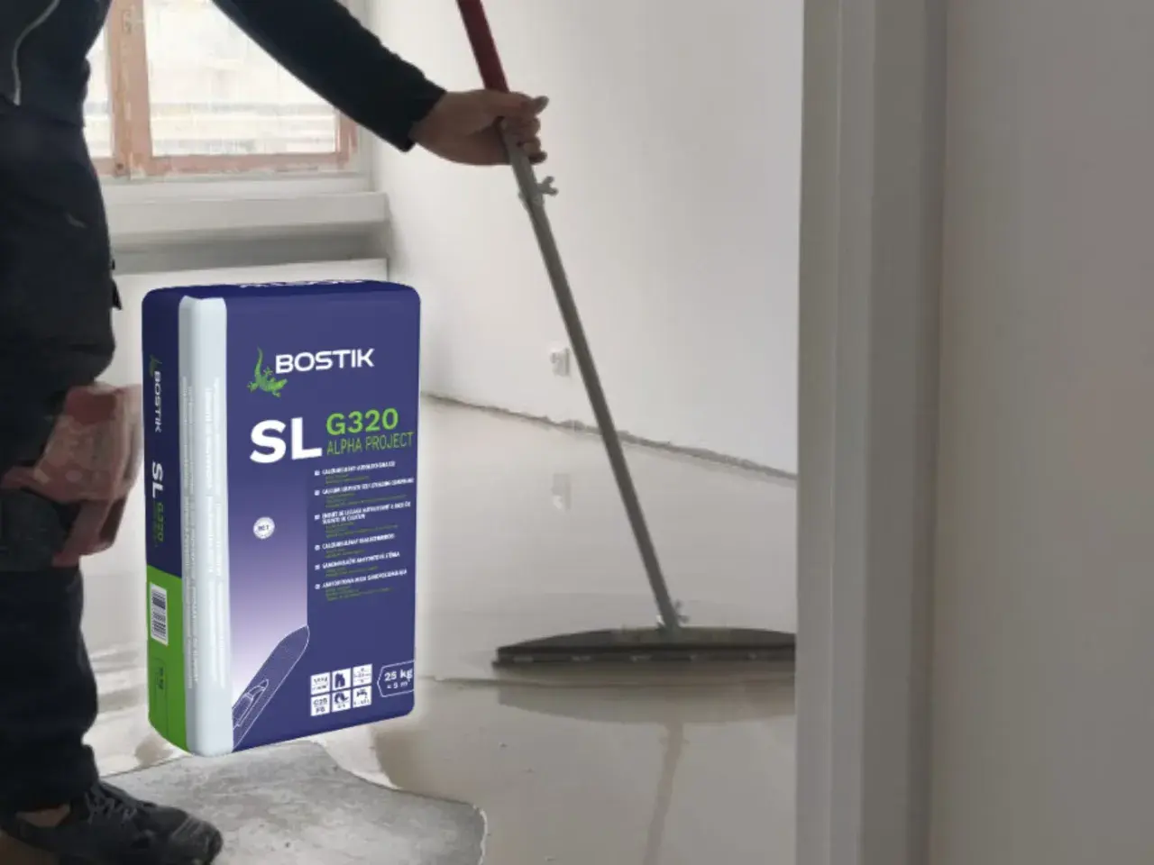Pracownik rozlewa masę samopoziomującą Bostik SL G320, by wyrównać posadzkę.
