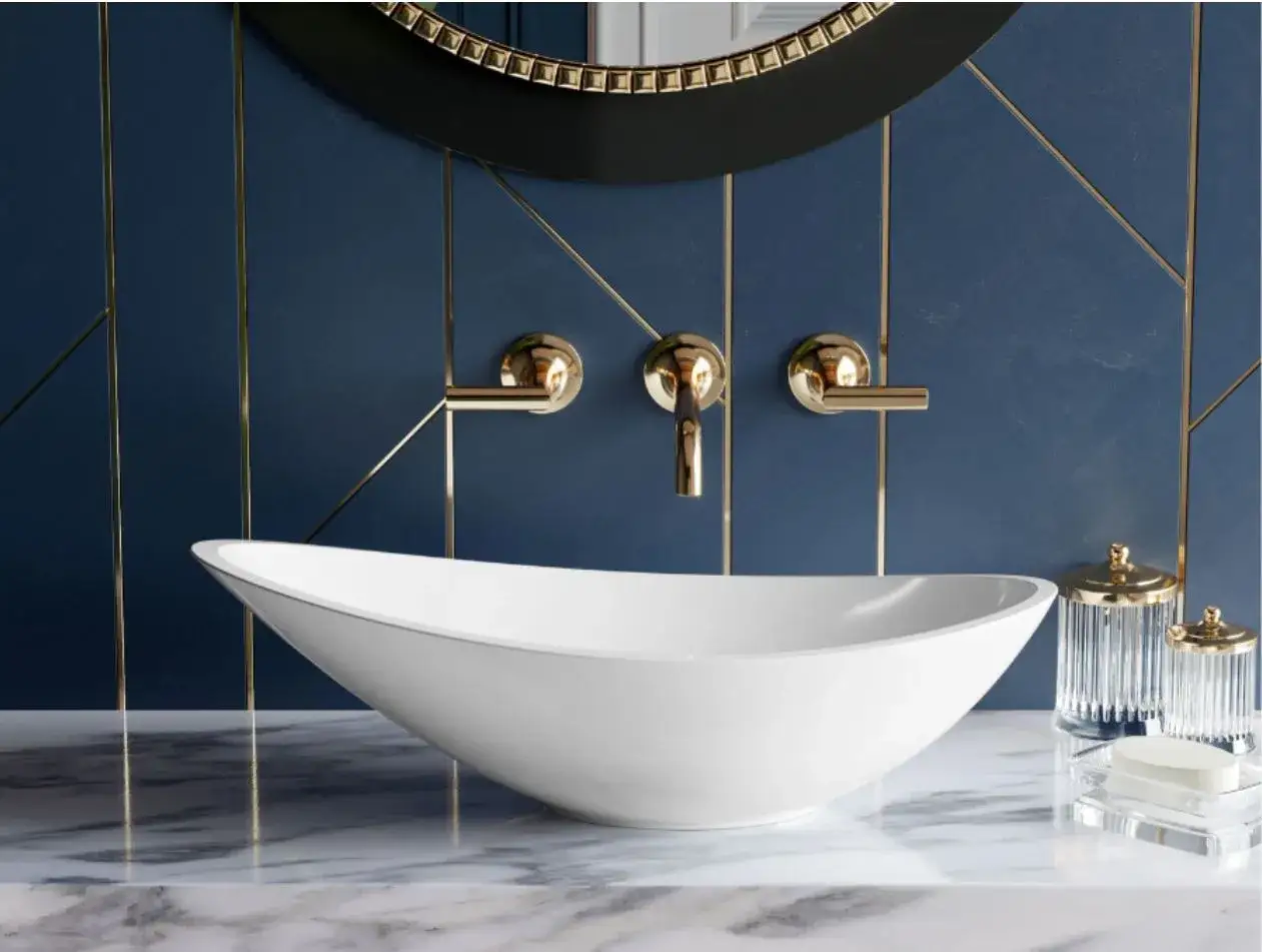 Elegancka łazienka z białą umywalką o futurystycznym kształcie, złotą armaturą i granatową ścianą z geometrycznymi złotymi liniami. Bocchi w nowoczesnym wydaniu.