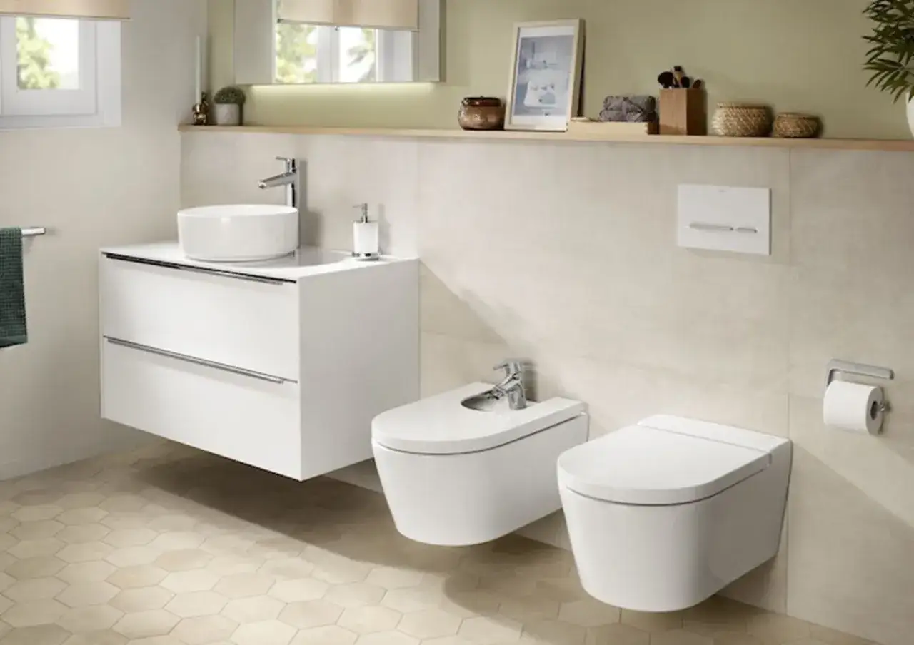 Nowoczesna łazienka z umywalką, bidetem i toaletą Roca. Eleganckie, białe ceramiki i minimalistyczne baterie.